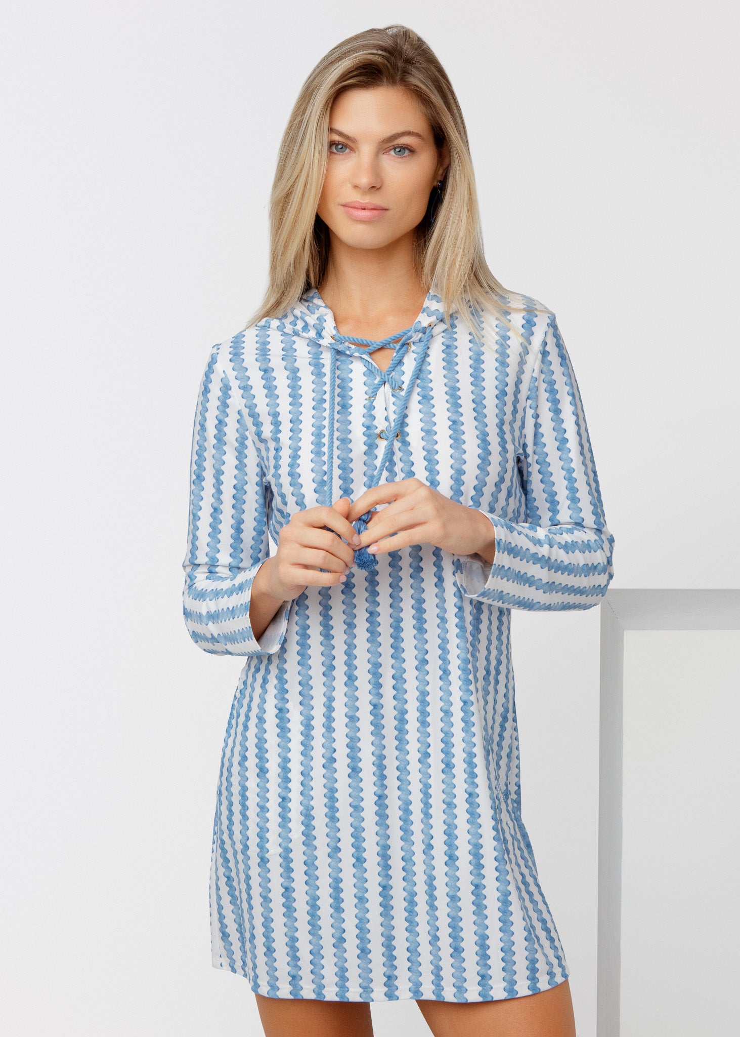 Woman wearing a blue and white striped cover up against a plain background