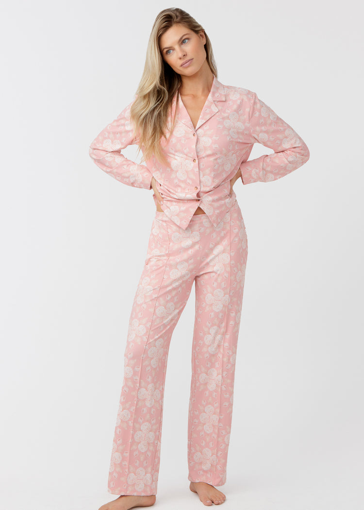 Woman standing with her hands on her hips, wearing our Coast pink and white shell patterned sleep to street pajama set on a white background.