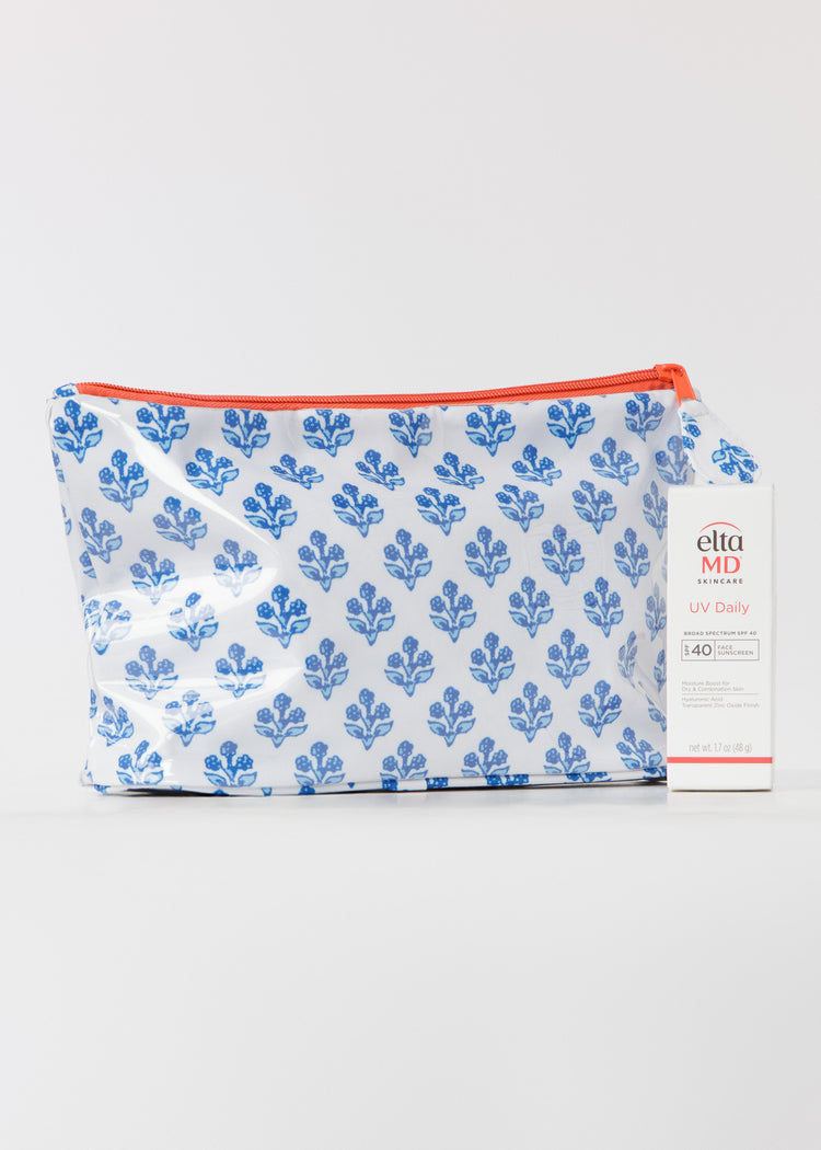 Small accessory bag with blue floral pattern and orange zipper on a white background with a box of SPF in front.