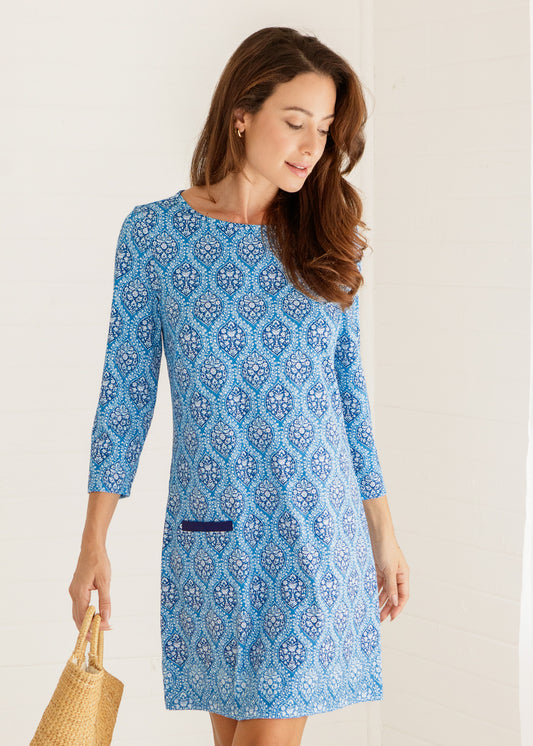 Woman wearing a blue patterned dress against a plain background