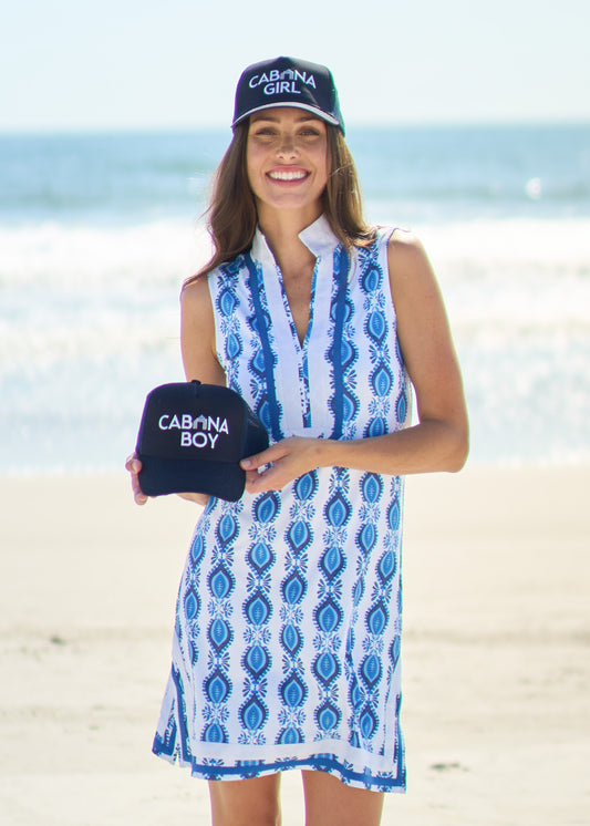 Woman wearing San Sebastian Sleeveless tunic Dress with Cabana Girl Hat on beach holding the Cabana Boy Hat.