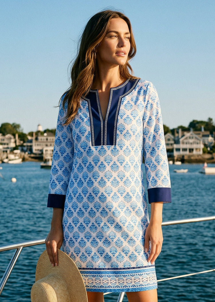 Woman wearing a blue and white patterned dress on a boat with a harbor background