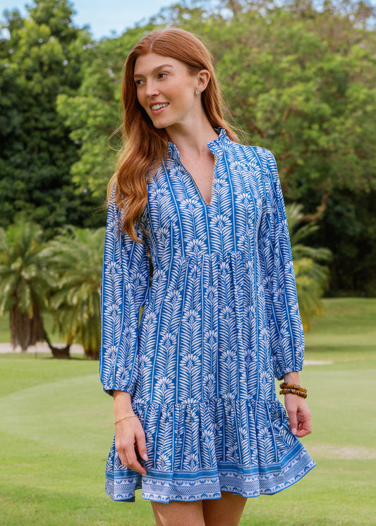 Woman wearing a blue patterned dress standing in a grassy area
