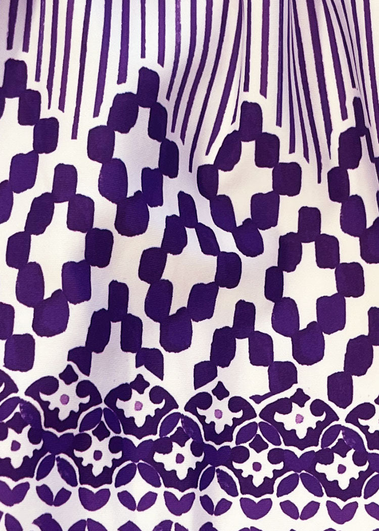 A close-up of a white fabric with a bold purple geometric and floral pattern.
