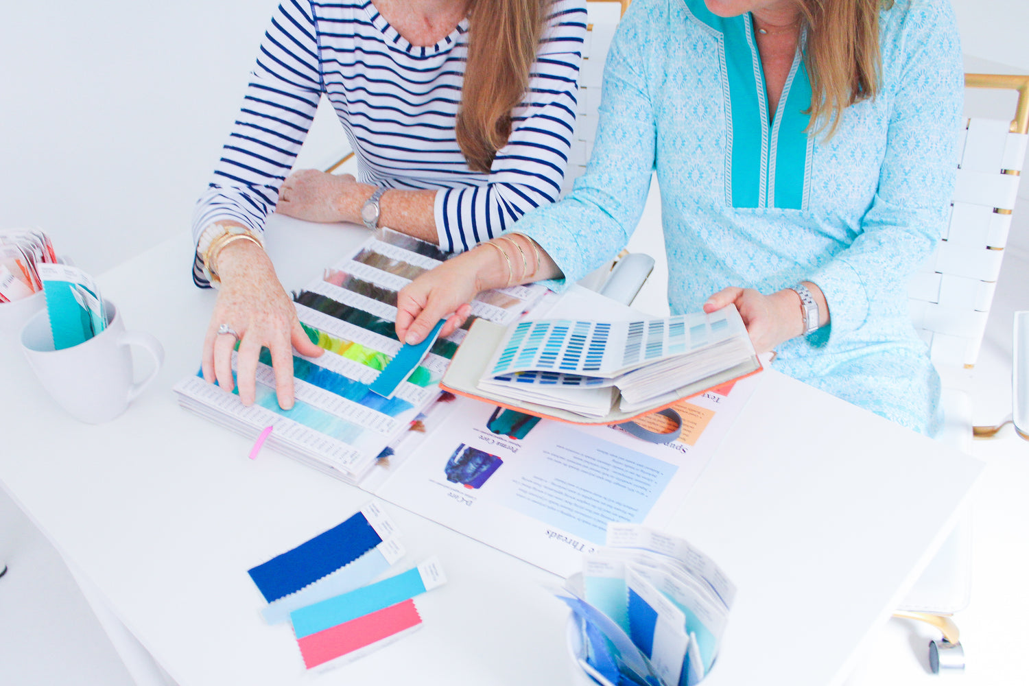 Women's hands looking at pantone chips & books on desk