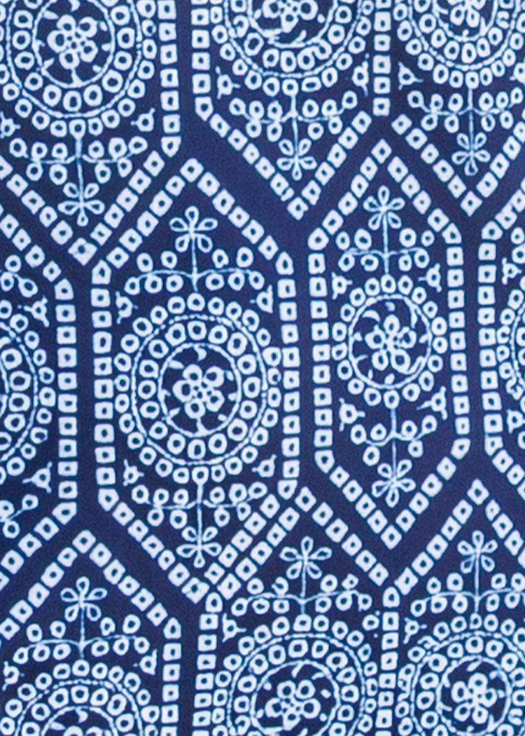 A close-up of a blue and white patterned fabric with a repeating geometric and floral block-print style design.