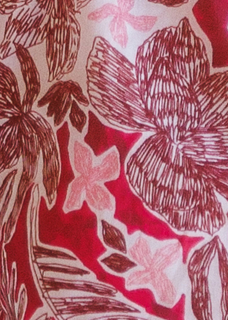 A close-up of a fabric or wallpaper pattern featuring stylized tropical floral motifs in dark red, pink, and cream.