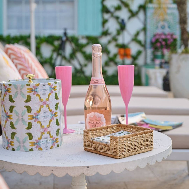 Bottle of Prosecco with two pink flutes and a decorative box on a table outdoors.