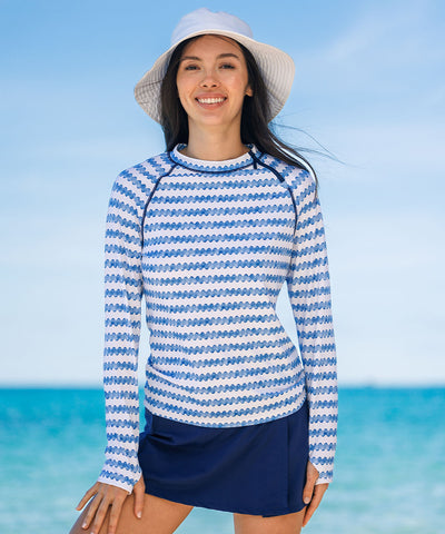 Woman on the beach wearing sun protective rashguard and swim skirt.