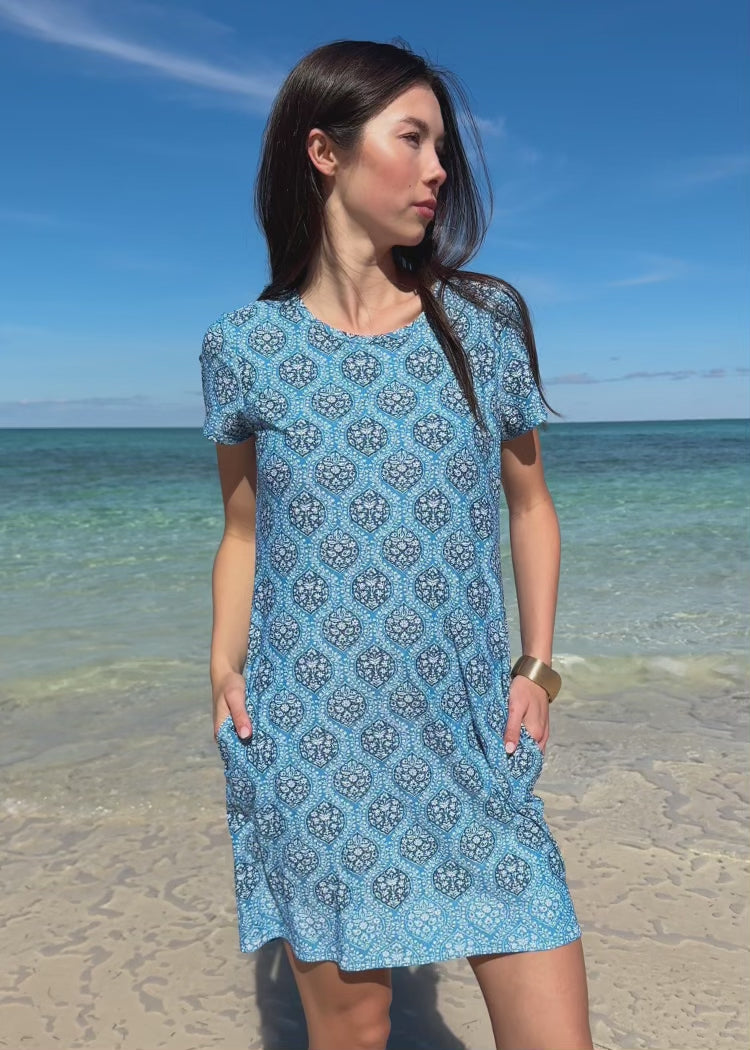 Video of a woman wearing a blue printed dress on the beach