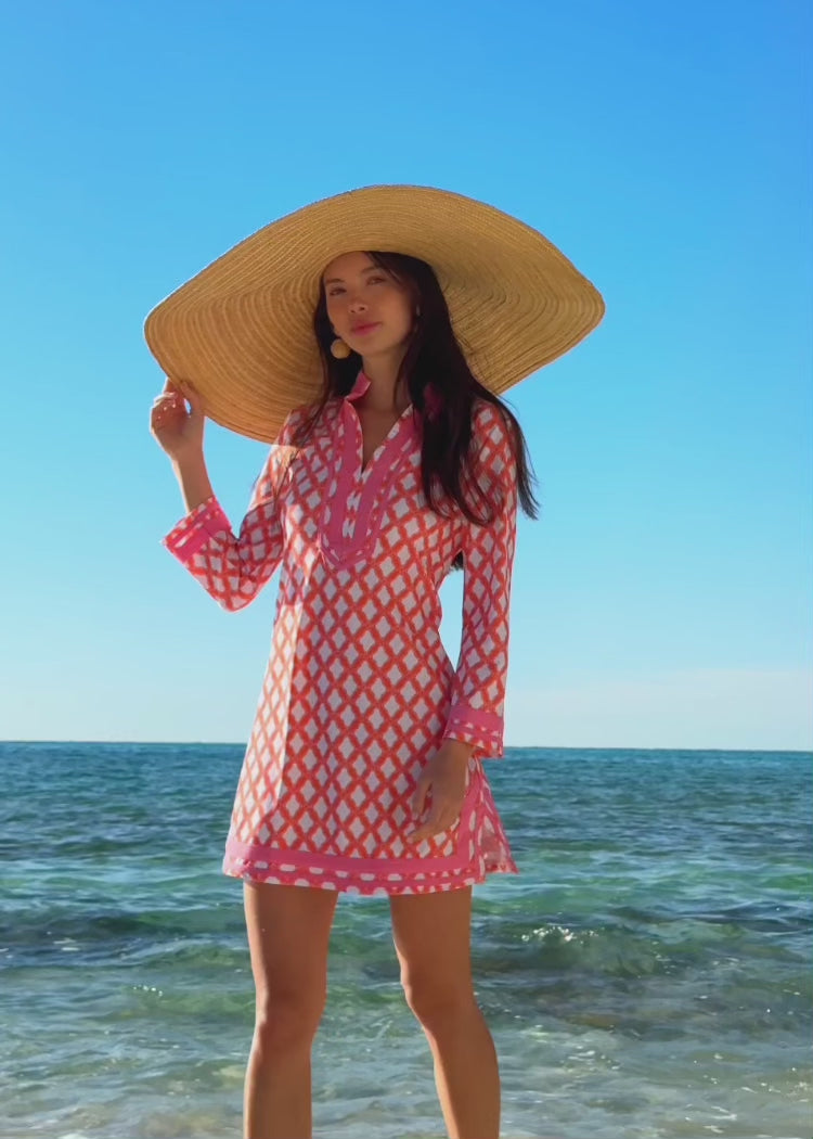 Video of a woman wearing a coral printed dress on the beach