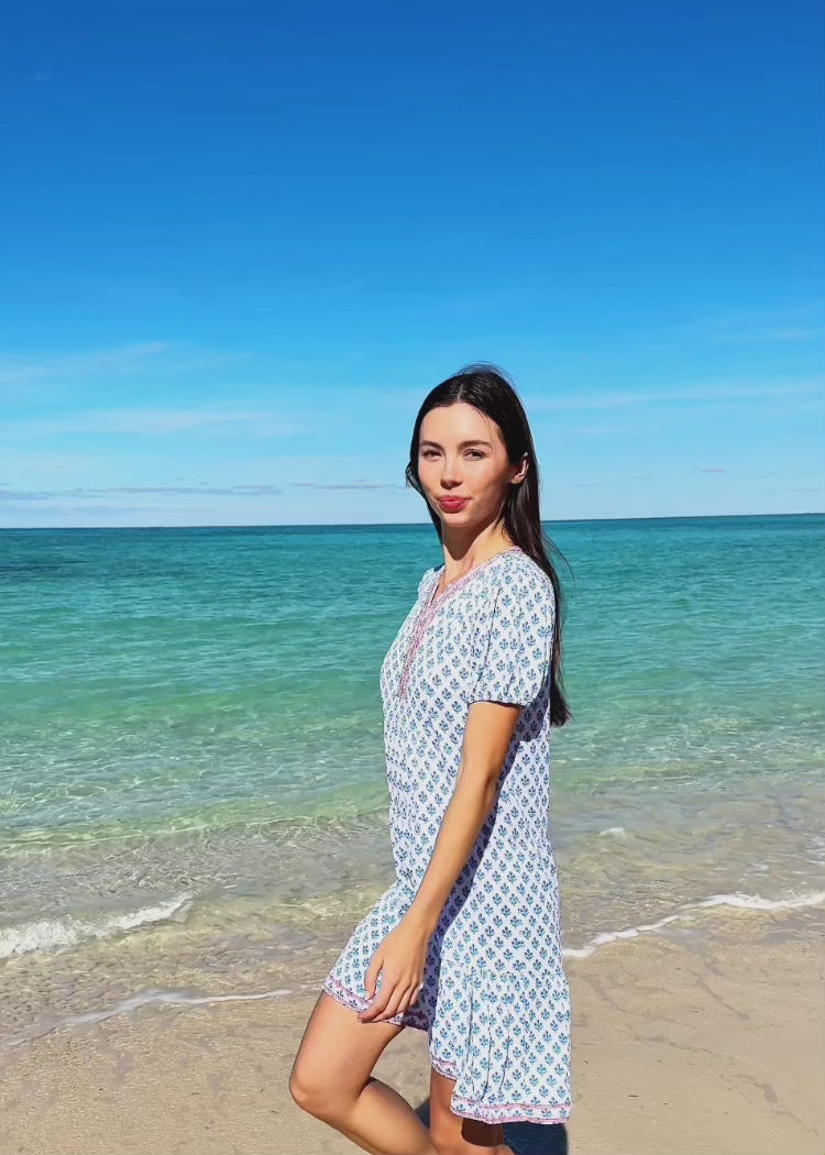 Video of a woman wearing a blue printed dress on the beach