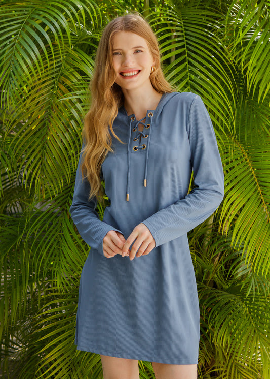 Woman wearing a blue cover up with lace-up details against a green leafy background