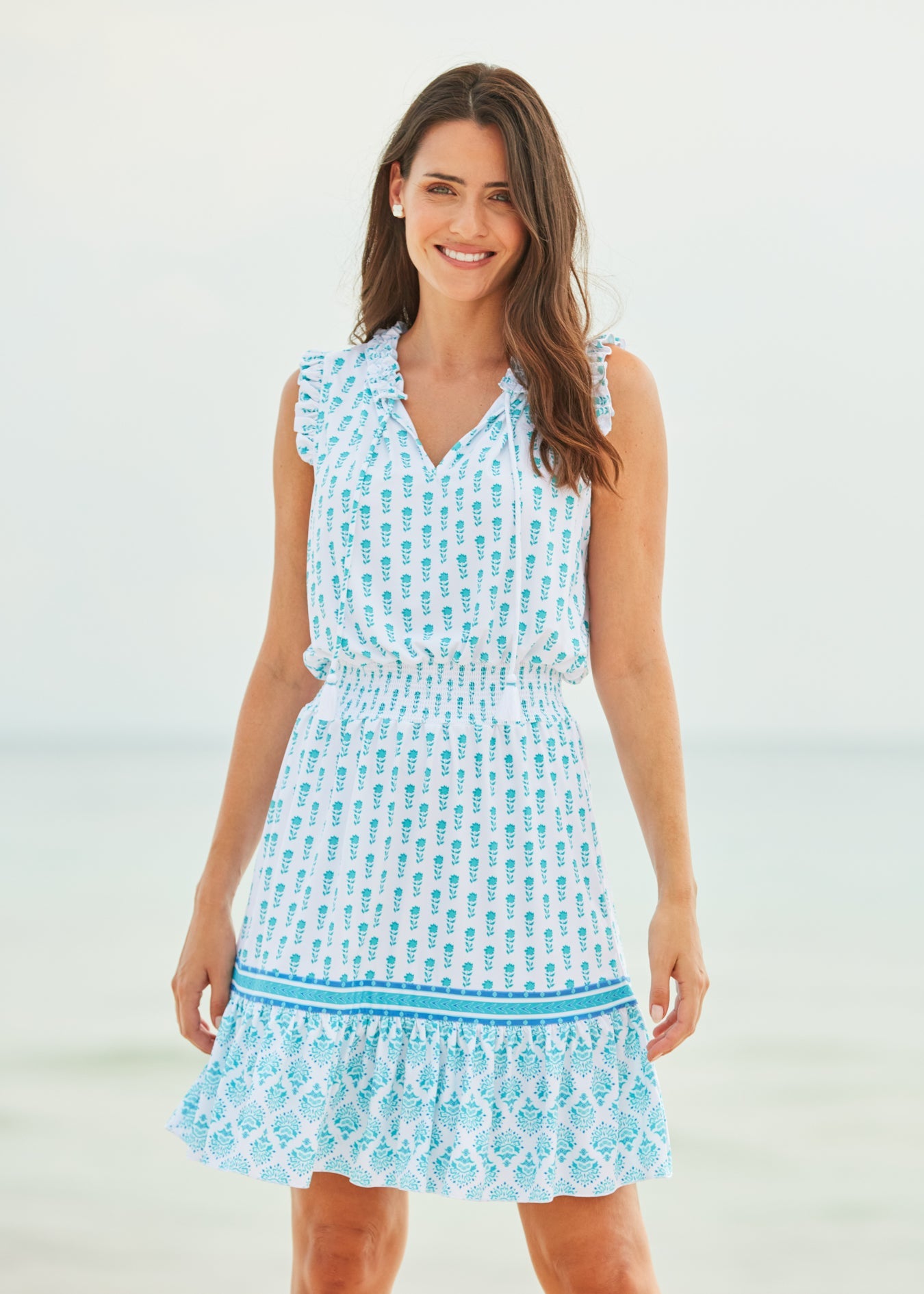 Brunette woman wearing Amalfi Coast Sleeveless Ruffle Dress on beach