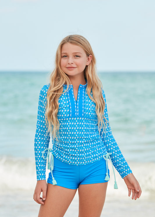 Girl in front of the ocean wearing Palm Valley 3-Piece Front Zip Rashguard Set.