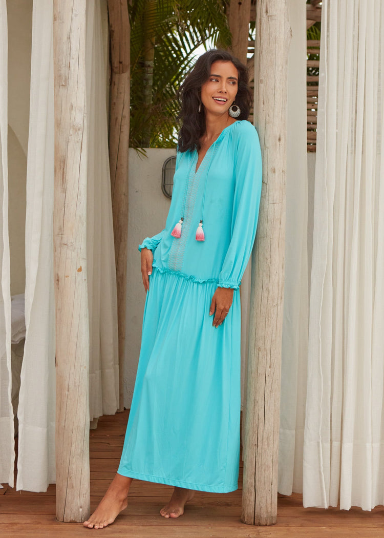 A woman wearing the long, flowy, bright aqua and sun protective Cabana Life Aqua Embroidered Tunic Maxi Dress. 