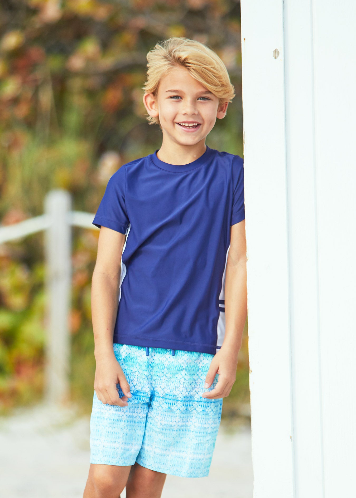 Boy wearing Cabana Life Boys Navy Short Sleeve Rashguard with Boys Coastal Cottage Swim Trunks