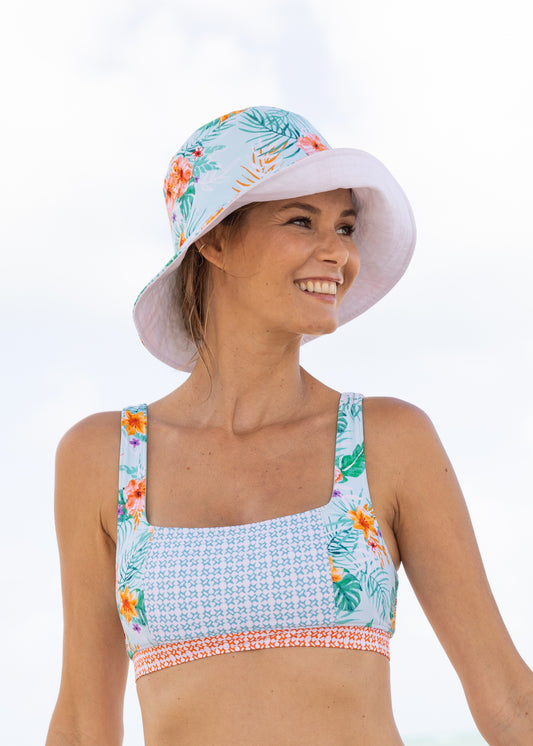 Woman wearing Cayman/White Reversible Bucket Hat and Cayman Reversible Bikini Top on beach