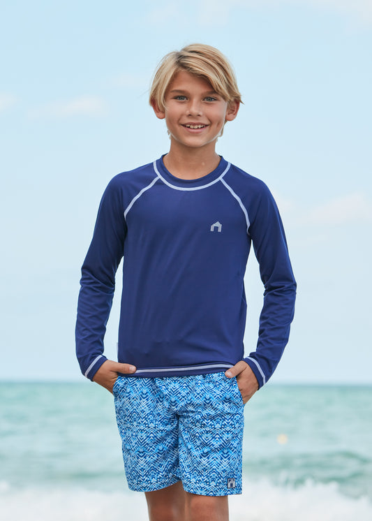 Boy wearing Coral Springs Swim Trunks and Navy Long Sleeve Rash Guard.