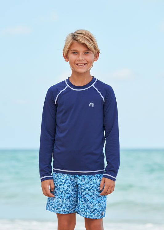 Boy wearing Coral Springs Swim Trunks and Navy Long Sleeve Rash Guard.