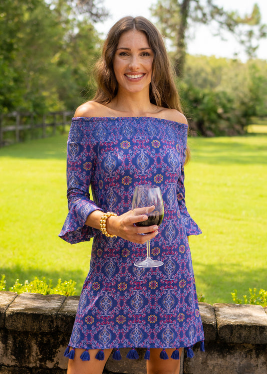 Woman wearing Seattle Off The Shoulder Dress in front of stone wall and field holding wine glass