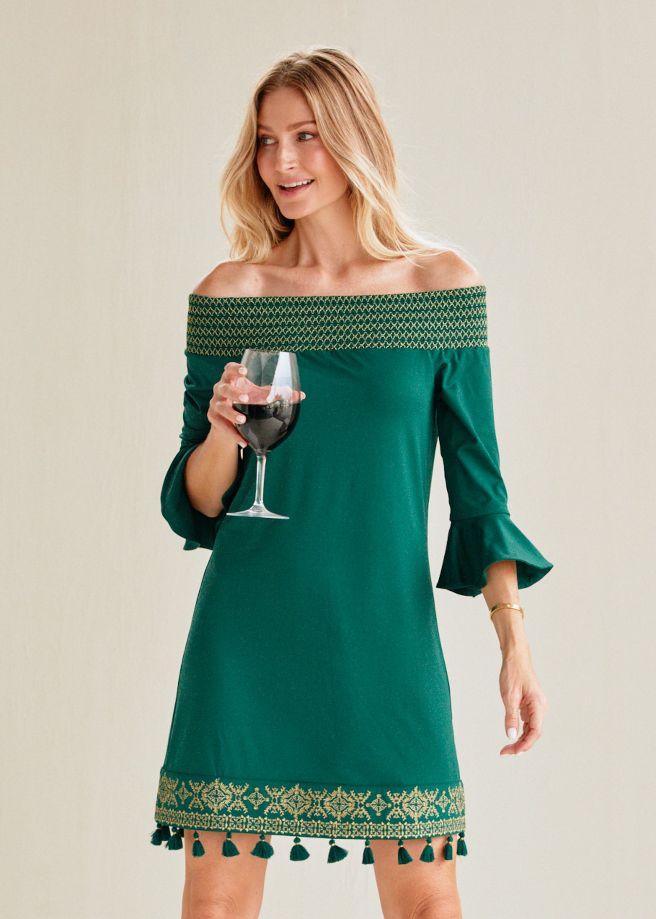 Festive woman in emerald green with gold off the shoulder dress.