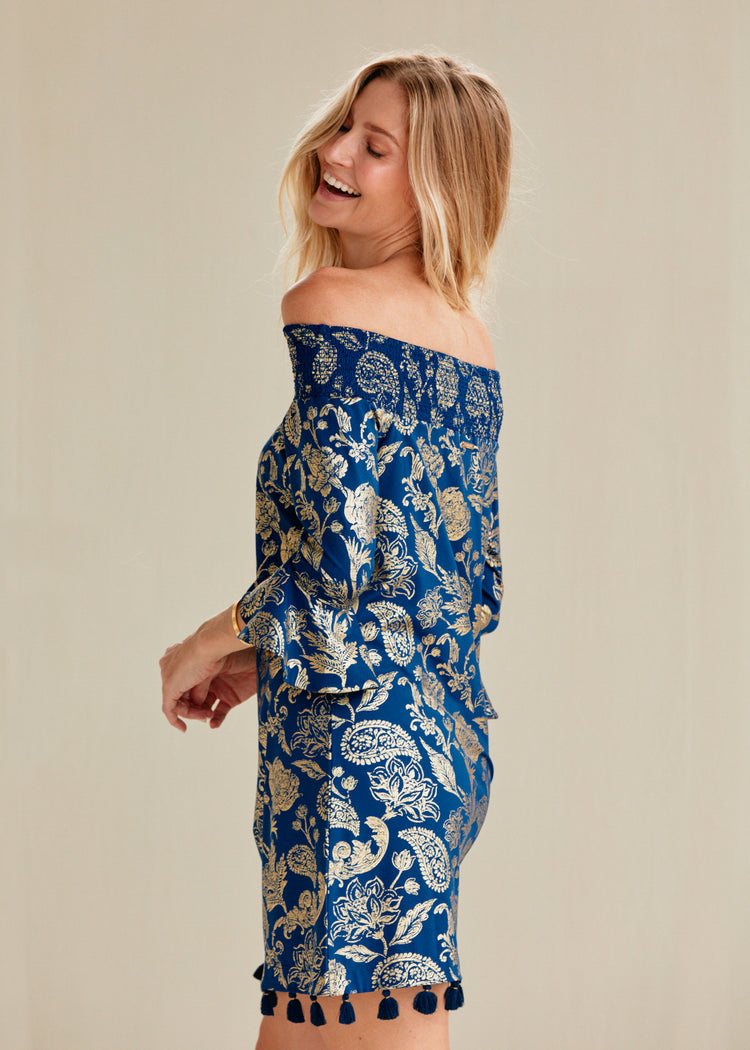 Woman in navy and gold metallic paisley print off the shoulder dress.   