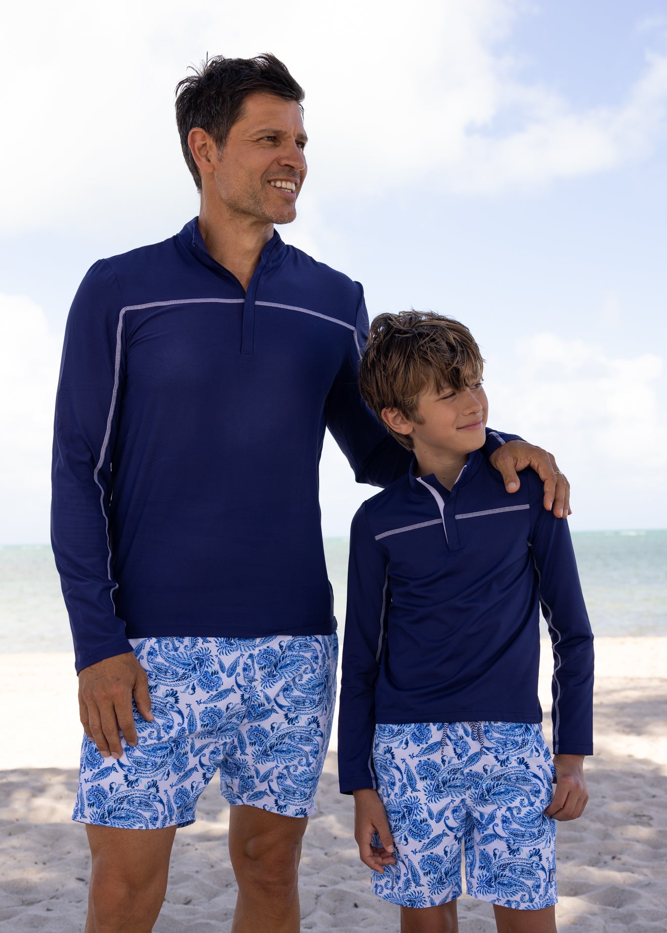 Father and son on beach wearing Men's Charleston Paisley Swim Trunks with Men's Navy Sport Zip Top and Boys Navy Sport Zip Top with Boys Charleston Paisley Swim Trunks